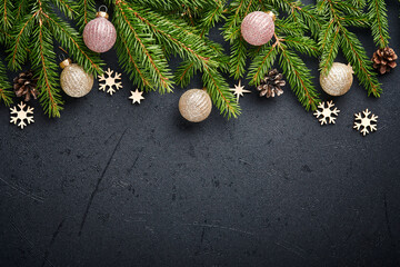 Christmas Decoration. Holiday Decorations with baubles, fir branches and present on dark black background. Border design. Top view.
