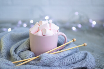 knitting needles, a cup of coffee with pink marshmallows.Christmas lights