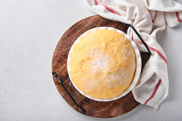 Raw yeast dough with pumpkin in white bowl covered with towel on the floured kitchen table, recipe idea. Concept home baking bread, buns or cinnabon or making dough.