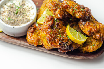 Delicious onion bhaji fritters served on wooden plate with white dip