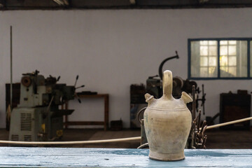 Selective focus on an old jug, inside a factory. 
