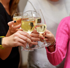 Celebration concept.People hands toasting with champagne glasses at delicious feast outdoors in the evening. Family and friends clinking glasses and cheering with alcohol