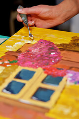 Cropped image of artist woman's hand drawing an oil color on canvas by palette knife at the modern art studio. Young artist concept.