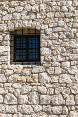 Fototapeta na wymiar Window with wrought iron bars in the stone wall.