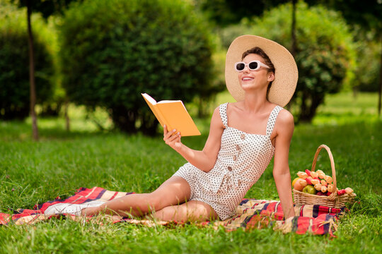 Full size photo of young charming adorable happy positive woman sit blanket green read book glasses outside outdoors park