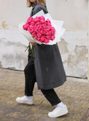 Woman with bunch of pink spray roses. Young woman holding a big bouquet of pink spray roses in Women's day. Fresh beautiful flowers bouquet.