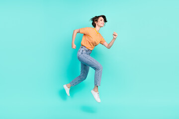 Photo of pretty charming young woman dressed striped t-shirt smiling jumping running empty space isolated teal color background