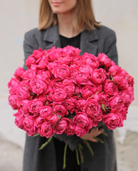 Woman with bunch of pink spray roses. Young woman holding a big bouquet of pink spray roses in Women's day. Fresh beautiful flowers bouquet.