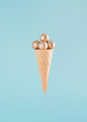 Creative arrangement made of an ice cream cone and Christmas baubles on a blue background. Minimal New Year concept. Summer Christmas inspiration.
