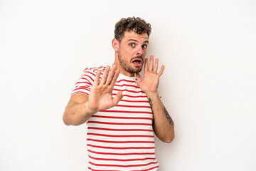 Young caucasian man isolated on white background being shocked due to an imminent danger