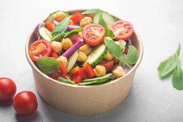 Vegetarian chickpea beans salad prepared with tomatoes and cucumber in a paper bowl,close up. Zero waste dishware