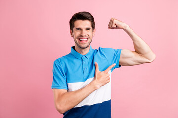 Photo of young smiling sportive strong male showing muscles recommend healthy life isolated on pink...