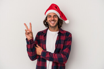 Young caucasian man celebrating Christmas isolated on gray background showing number two with fingers.