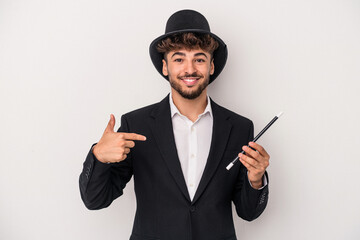 Young arab wizard man holding a wand isolated on white background person pointing by hand to a...
