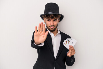 Young arab wizard man holding a magic cards isolated on white background standing with outstretched...