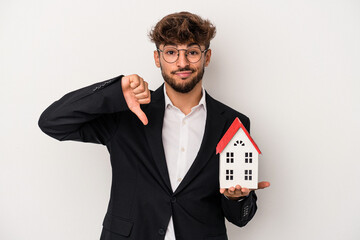 Young arab real estate man holding a model house isolated on isolated background showing a dislike...