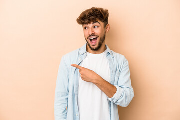 Young arab man isolated on beige background looks aside smiling, cheerful and pleasant.