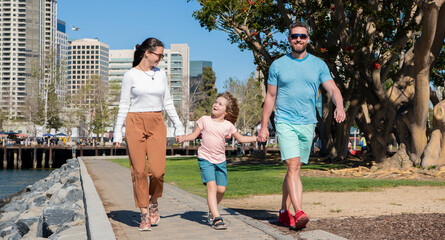 happy young mom and daddy walking in park with son, charity