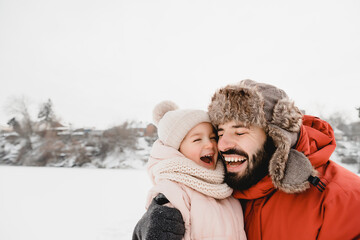 Young stylish bearded Father and baby Daughter On Winter Vacation. Father giving son ride on back in park. Happy, joyful family. Happy, joyful family.