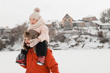 Happy father and baby son having fun under sunny winter snow, holiday season