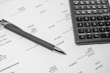  ballpoint pen and a calculator lie on a financial evaluation