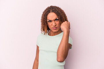 Young latin transsexual woman isolated on pink background showing fist to camera, aggressive facial...