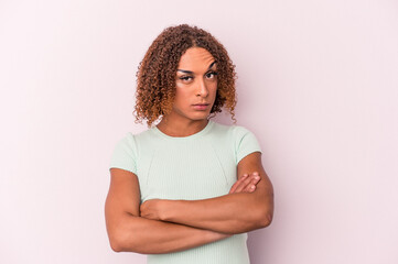 Young latin transsexual woman isolated on pink background unhappy looking in camera with sarcastic expression.