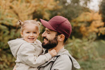 Happy father and daughter playing while walking in a beautiful autumn park. Ideal weekend father with his little daughter. selective focus, noise effect..