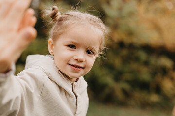 portrait of a little cute girl which shows the palm in the autumn park