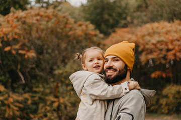 Happy father and daughter playing while walking in a beautiful autumn park. Ideal weekend father with his little daughter, autumnal mood