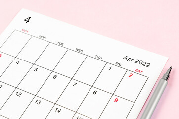 April 2022 calendar sheet with pen on pink background.