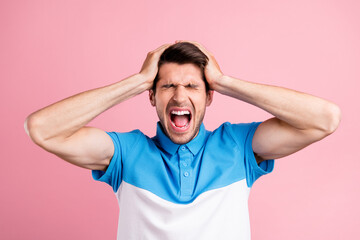 Portrait of young stressed annoyed man screaming have headache suffering isolated on pink color...