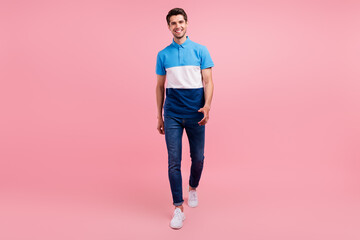 Fototapeta na wymiar Full length photo of positive brunet millennial guy go wear polo jeans sneakers isolated on pink background