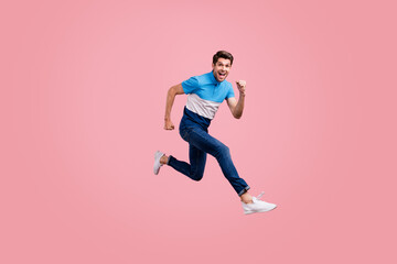 Full length photo of crazy brunet millennial guy run wear polo jeans sneakers isolated on pink background