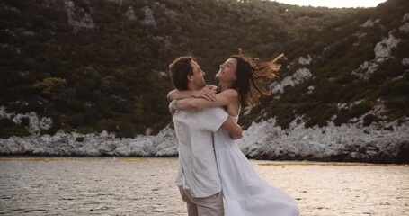 Happy caucasian couple hugging and kissing on beach enjoying romantic honeymoon vacation