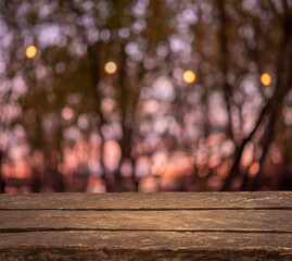 Empty old vintage wooden table. Bokeh colorful sunset and forest trees. String of lights. Template mock up for display of product