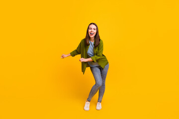 Photo of funny charming young lady wear green shirt smiling dancing isolated yellow color background