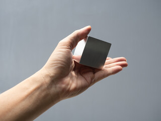 metallic cube reflecting and shining light on human hand