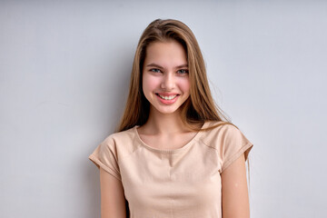 Portrait of beautiful caucasian teenage girl isolated on white background, smiling happily, in casual wear, enjoying life, in good mood, posing at camera, having natural long hair and big lips.