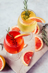 Red and white aperol spritz garnish in wine glasses with rosemary and grapefruit on luxury marble...