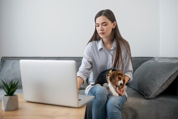 Young dark-haired woman with a cute puppy at home