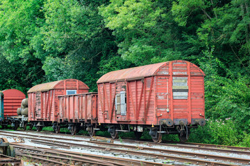 Fototapeta na wymiar old abandoned damaged and weatherd wooden red train cars