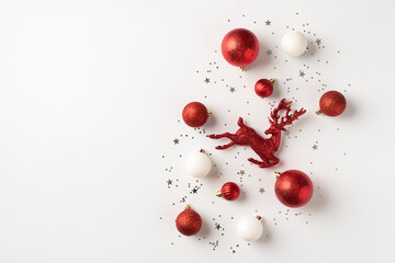 Top view photo of red and white christmas tree decorations balls reindeer and silver confetti on isolated white background with copyspace