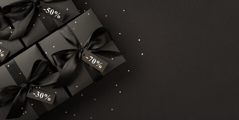 Top panoramic view photo of black gift boxes with black satin ribbon bow tags and sequins on...