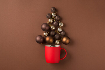 Top view photo of brown silver and gold christmas tree balls flying out of red cup on isolated brown background