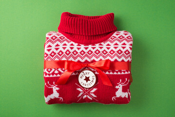 Top view photo of folded red and white christmas sweater with red ribbon bow and label with...