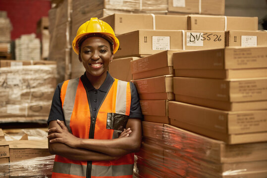 Smiling African female warehouse worker leaning against some boxes