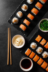 set of rolls with salmon, sauce, wasabi, hiashi wakame on a dark background