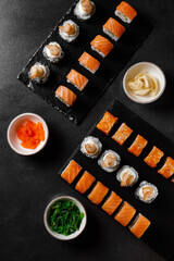 set of rolls with salmon, sauce, wasabi, hiashi wakame on a dark background