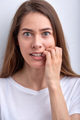 Close-up Portrait of worried surprised caucasian woman keeping hands on mouth, concerned, isolated over white studio background. People face expressions and reaction concept. Nervous female at a loss